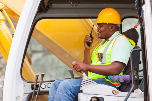 african industrial worker operating bulldozer while talking on walkie-talkie