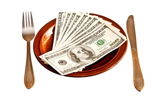Money on the plate with fork and knife, isolated on white background
