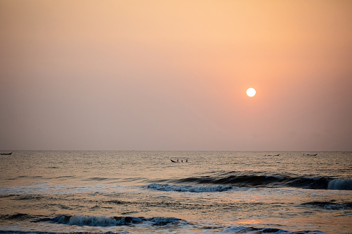 Sun rises over the Bay of Bengal, boats in the distance
