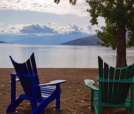 Two Adirondack chairs on  sandy Kin beach Okanagan Lake, Vernon BC.