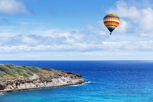 Hot air balloon over cape with cloudy blue sky