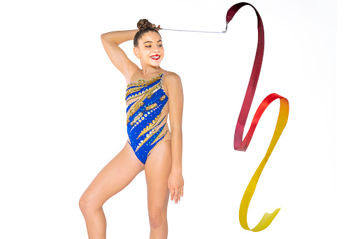 Exercises with clubs. Young graceful girl, female rhythmic gymnast training isolated over white background. Concept of action, motion, sport life, competition. Copyspace for ad.