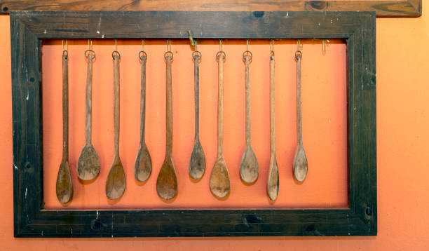 Wooden kitchen utensils frame on a wall background. Wooden spoons hanging on a cutting board