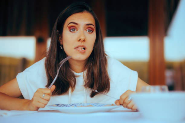 hungry woman holding a fork and knife thinking what to eat - esfomeado imagens e fotografias de stock
