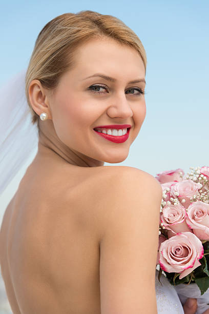 istock Bride In Backless Dress With Flower Bouquet Against Clear Sky 176231349