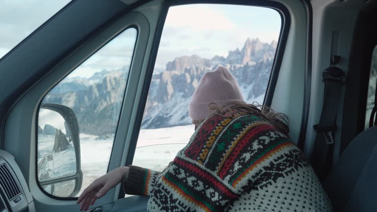 Woman in knitted sweater sitting in  the camper van in winter