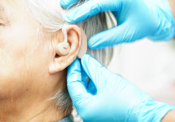 istock Doctor install hearing aid on senior patient ear to reduce hearing loss problem. 1762344781