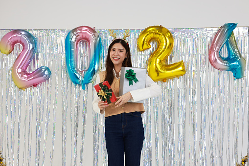 Portrait  of the happy young woman shows a present box  on New Year isolated multi-color background