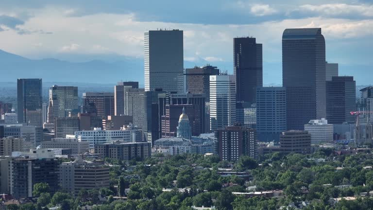 Cityscape of Denver with Colorado mountain ranges backdrop; skyscrapers. Long zoom lens on drone. Aerial shot with capitol building.