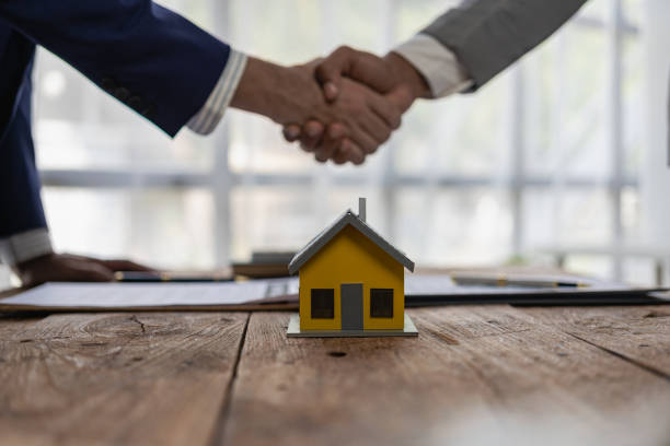 real estate agent shakes hands with client after the contract is finalized after home insurance and investment loans. agent and client shake hands after signing the contract to buy a home. - house real estate residential structure insurance imagens e fotografias de stock