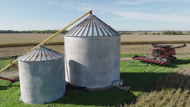 Grain Bin Silos and Combine Harvester in a Rural Farm Field, Aerial