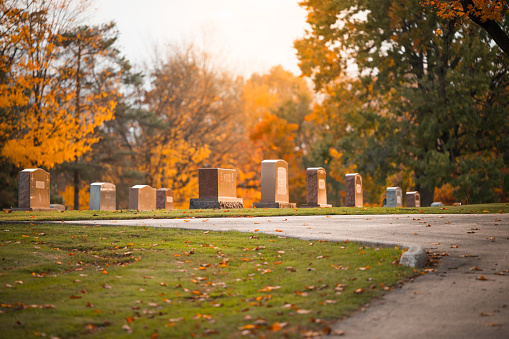 Beautiful autumn cemetery with old and new grave stones with walking path
