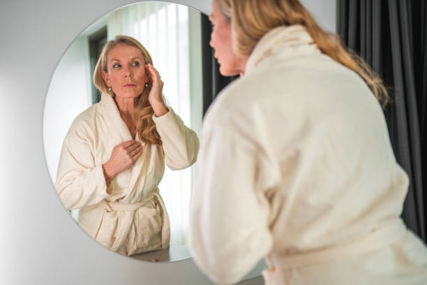 istock Lovely Mature Caucasian In A Bathrobe Looking At A Mirror 1762410408