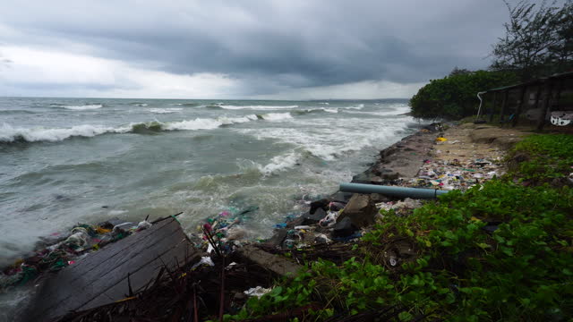 Strong Waves Crash Against Damaged Coastal Wall with Surrounding Ocean Trash and Pollution