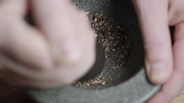 To cook a fantastic dinner a chef crush black pepper in a mortar. Close-up, no face.