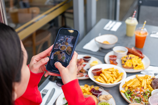 Young woman taking a photo of brunch food