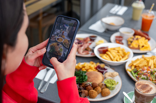 Young woman taking a photo of brunch with smart phone