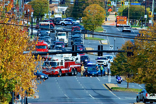 Fairfax, Virginia, USA - October 26, 2023: An ambulance departs the scene of an accident as first responders remain to investigate.