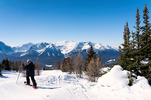 Woman snowshoes across snowy mountain at Lake Louise, Banff National Park, Alberta, Canada