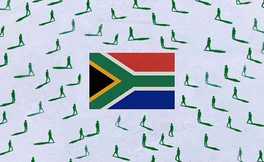 complete national flag of south africa covers whole frame, waved, crunched and very natural looking. In front plan is clenched fist symbolizing determination