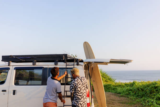 istock Two Friends Setting Up Tent on top of a Camper Van at Sunset 1762641108