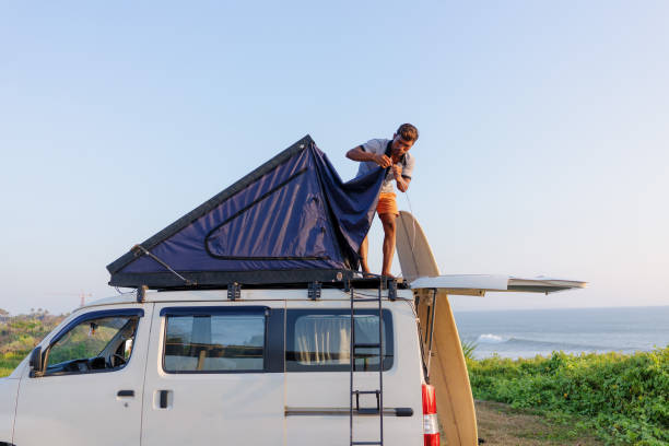 istock Indonesia Man Setting Up Tent on top of a Camper Van at Sunset 1762642253