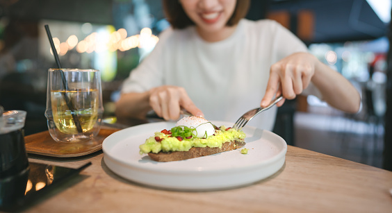 Guacamole avocado healthy food top on bread toast. Asian woman background at indoor restaurant on day. City people lifestyle on weekend concept.