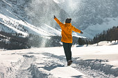 Happy woman girl jumps and throws snow in mountains