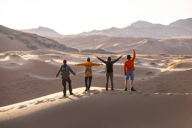 Four happy tourists stands on sandy dune