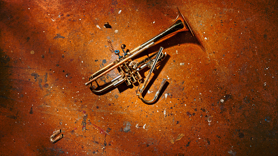 Overhead view of broken trumpet lying on floor.