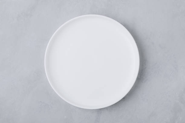 istock White round empty ceramic plate on gray concrete stone background. 1762744639