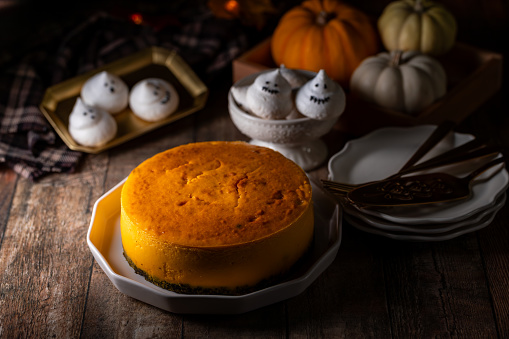 Fresh delicious pumkin cheesecake decorated with festive Halloween theme background.