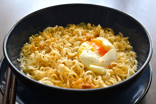 Instant noodles with egg in a bowl. Noodle soup with poached egg and seasonings. Asian food style.