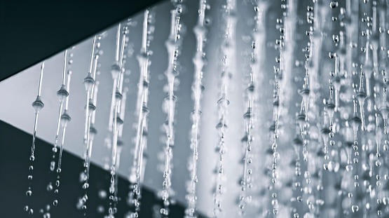 Low angle view of water flowing from shower head in bathroom.