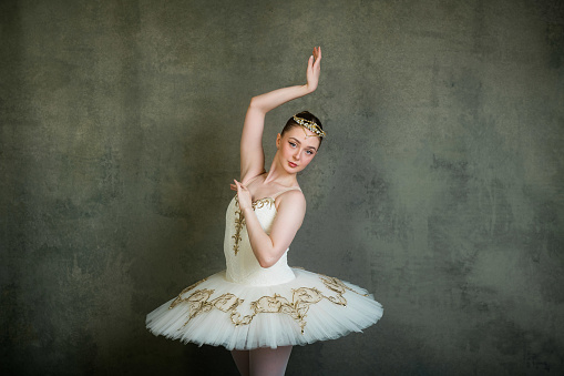 Professional ballerina in tutu standing en pointe in attitude pose. Professional make-up and hairstyle.