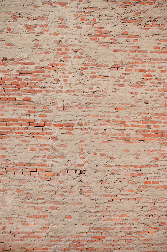 Old red brick wall with shabby paint. Brick background.
