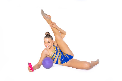 Teenage girl practicing rhythmic gymnastics doing ball exercises while taking a selfie and smiling