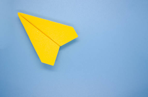 istock Top view of yellow paper airplane on blue background with customizable space for text. Copy space and plane concept 1762912781