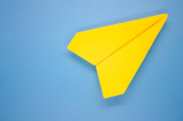 istock Top view of yellow paper airplane on blue background with customizable space for text. Copy space 1762912953