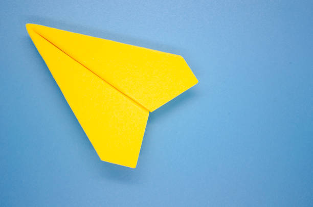 istock Top view of yellow paper airplane on blue background with customizable space for text. Copy space. 1762913311