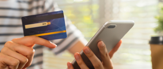 Primer plano de la mano sosteniendo la tarjeta de crédito y usando el teléfono inteligente con el pago en línea para ir de compras. photo