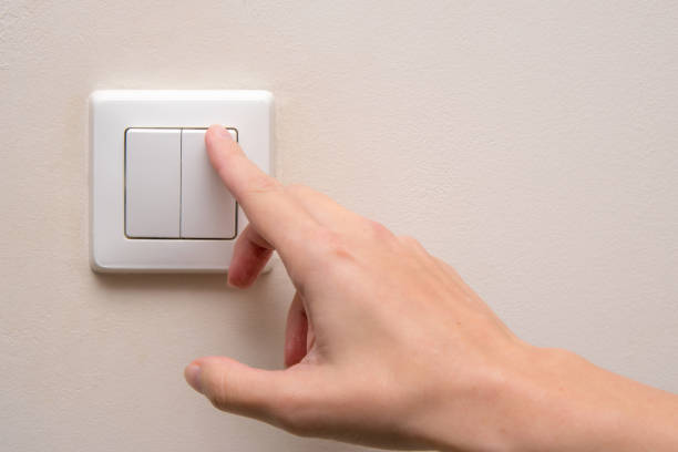 istock Woman turns on a light switch inside a room 1762933356