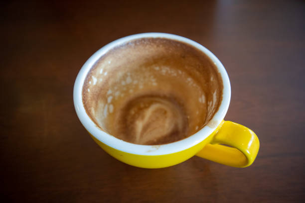 Latte coffee stains in yellow coffee cup on wooden table