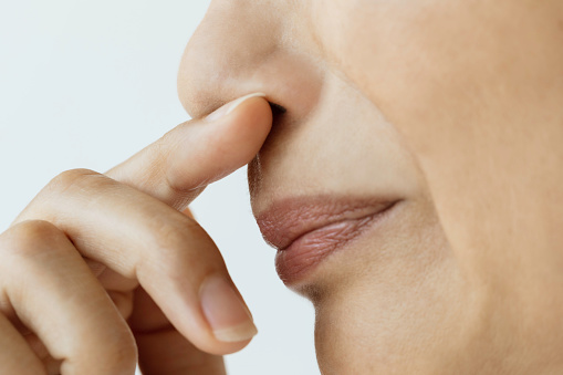 Caucasian female holding nose . Representing bad smell and disgust.