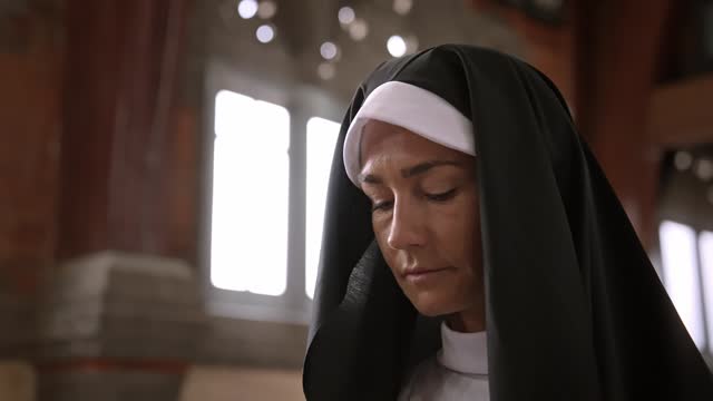 One Nun Woman Prays in Church and Thinks about Religion. Portrait of a Young Adult Sister Thinking about Faith and God. Rituals Inside the Church Building. Modern Christian at Sunday Prayer Close-up
