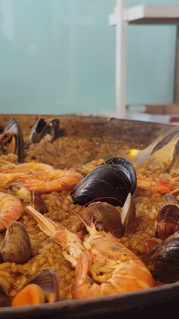 Closeup of a waiter serving a typical spanish seafood paella from the paellera. Vertical video