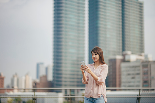 A young Asian woman uses a smartphone in the city