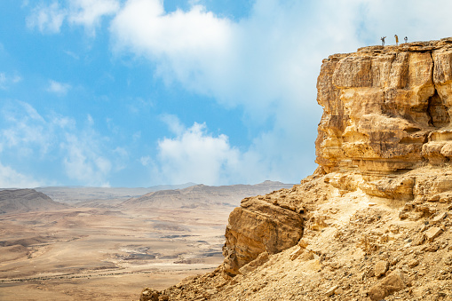Rock with small people on the top at Makhtesh Ramon, erosion crater landscape panorama, Negev desert, Israel