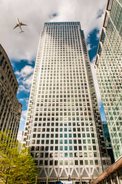 An aeroplane flies low over a tall skyscraper, London.