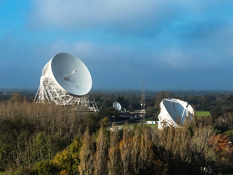 A closeup aerial photograph of Jodrell Bank, Cheshire, England. The photograph was produced on a bright autumn afternoon with clear blue skies. The photograph shows three radio telescopes of varying sizes at Jodrell Bank.